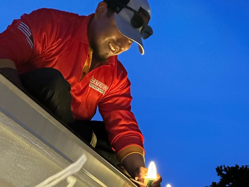 Professional Christmas light installer securing LED lights to a roofline in Tampa, FL