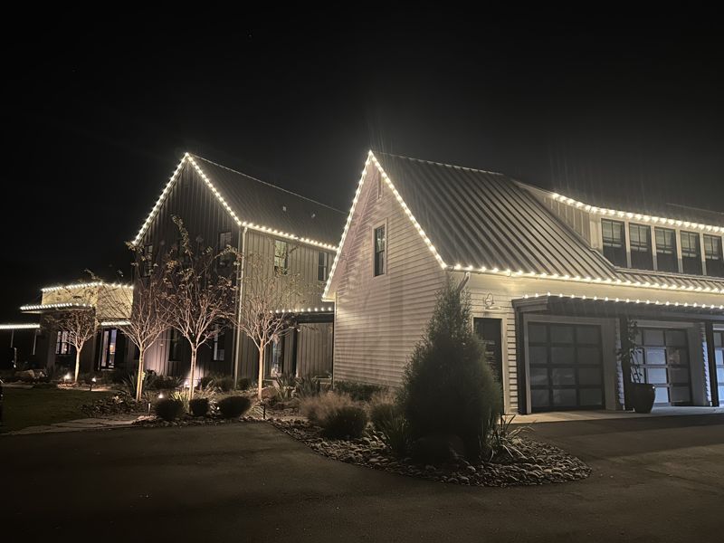Modern farmhouse with metal roof outlined in white LED Christmas lights